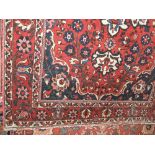 Persian style floor rug decorated with various floral medallions upon a deep red ground, 220 x 135