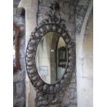 A Georgian style wall mirror of oval form the bevelled edge plate set within a cast metal frame with