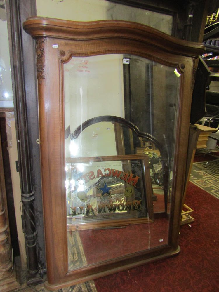 A late 19th century wall mirror the walnut frame with shaped outline and trailing floral detail