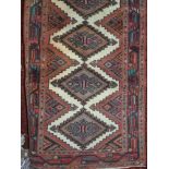 A Persian style wool runner with repeating lozenge central medallions on a red ground, 303 x 77 cm