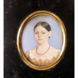 An early 19th century portrait miniature bust length study of a young girl wearing a coral