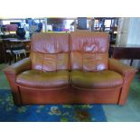 A two seat sofa upholstered in a pale brown leatherette covering.