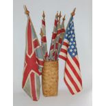 A collection of vintage flags, mainly Union Jacks, within a wicker basket.