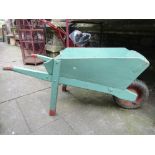 A vintage wooden wheelbarrow with mint green painted finish.