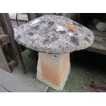 A cast composition stone saddle stone with weathered domed cap.