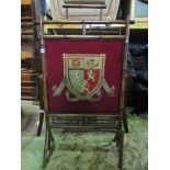 A Victorian bamboo fire screen incorporating a hand worked tapestry panel showing the coat of arms