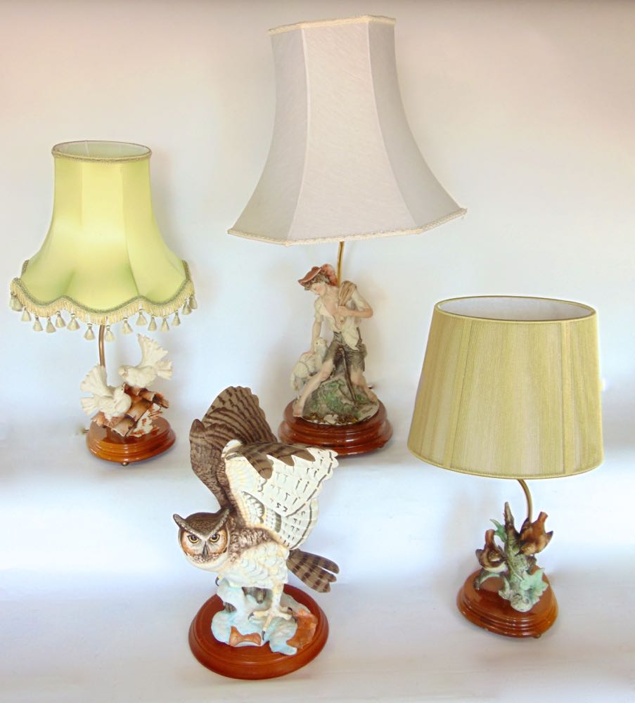 Three various figural porcelain table lamps, one modelled as a seated pauper boy, the other with