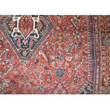 Good quality Eastern rug decorated with various geometric medallions upon a red and blue ground, 260