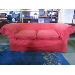 An Edwardian Chesterfield sofa with rolled back and arms and later brick colour loose covers