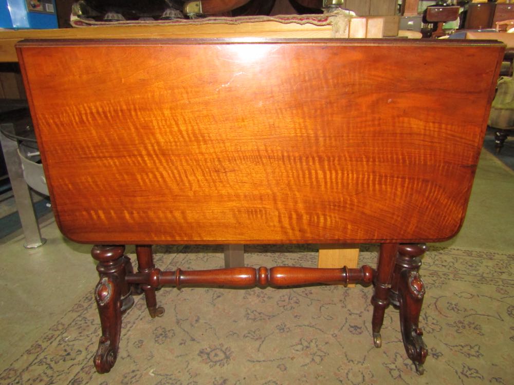 A Victorian walnut sutherland tea table of usual form raised on turned and fluted supports and feet