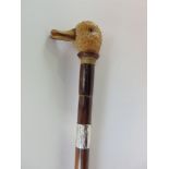 A walking cane with carved duckling head and knop, with glass eyes, the cane fitted with a silver