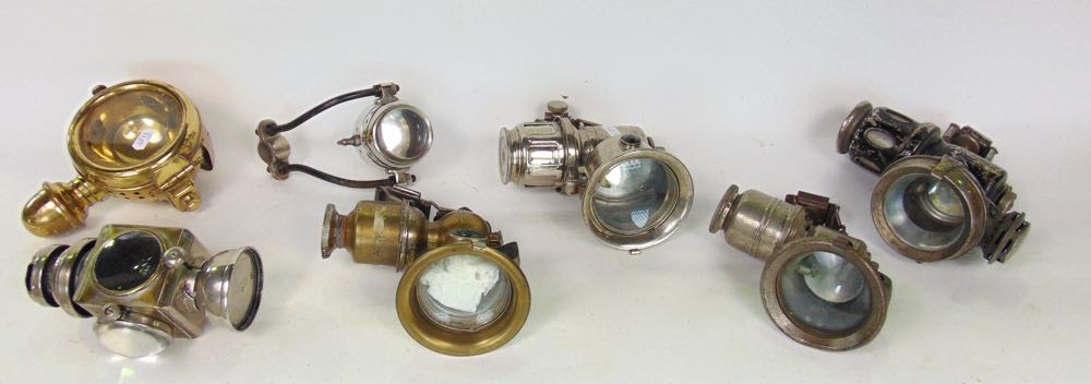 A box containing seven vintage motorcycle/cycle carbide lamps