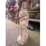A weathered cast composition stone garden ornament in the form of a female figure clutching a