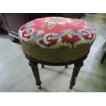 A Victorian stool with circular handwork top raised on four turned and fluted supports and