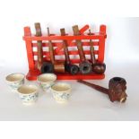 A collection of pipes on a pipe rack in the form of a painted red gate to include a carved pipe in