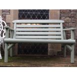 A rustic two seat garden bench with slatted seat and back and light green painted finish