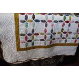 A vintage hand stitched quilt decorated with patchwork type floral panels upon a white ground.