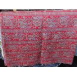 A vintage hand stitched quilt decorated on one side with paisley on a red ground, the other side