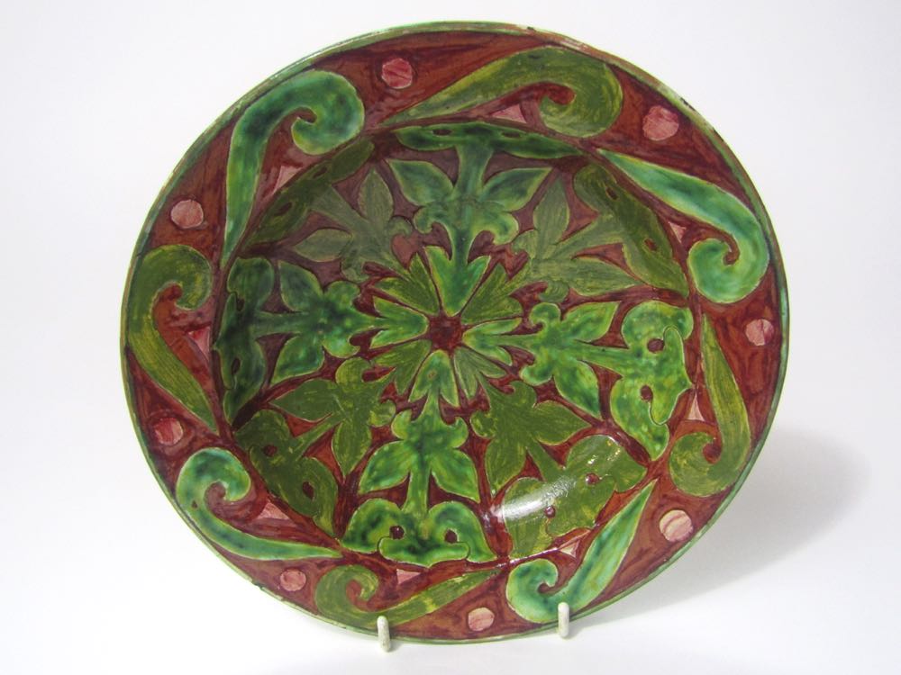 A 19th century Della Robbia dish with painted green strapwork style decoration on a brown ground and