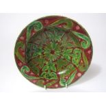 A 19th century Della Robbia dish with painted green strapwork style decoration on a brown ground and