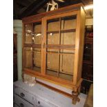 An early 20th century stripped oak bookcase freestanding and enclosed by a pair of quarter glazed