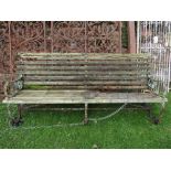 A vintage sprung steel framed garden/park bench with scrolled arms and weathered timber slatted seat