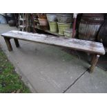 A weathered teak garden bench with planked seat raised on shaped and moulded supports, 83 inches