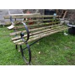 A sprung steel framed three seat garden bench with open scrolled arms and weathered timber open