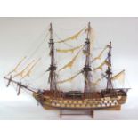 A scale model of a three mast battle ship fitted with canons and sails.