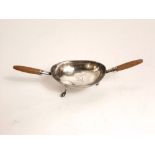An interesting antique twin handled white metal wine tasting bowl on three paw and ball feet, hall