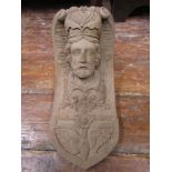 A well detailed carved corbal of a male bearded character wearing a hat, plus further scrolling