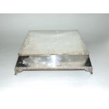 Silver plated square plinth type stand with gadrooned rim and cast scrolled feet, 13cm x 38cm wide
