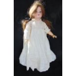 An antique bisque headed doll with shutting eyes, open mouth with four teeth and articulated