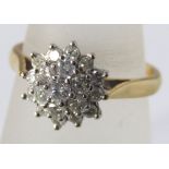 A diamond cluster ring marked 750, in white gold setting. 5.5g, size P/Q