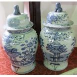 A pair of substantial oriental blue and white vases and covers with painted flowering tree and