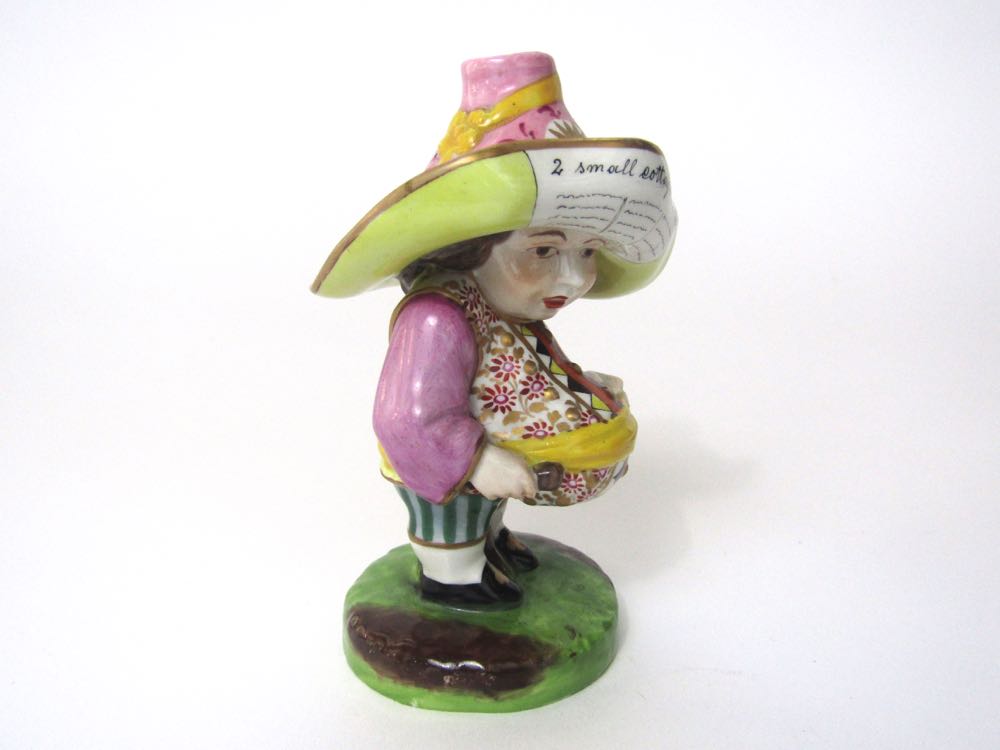 A 19th century figure of a Mansion House dwarf, in the Derby style, wearing a pink hat with yellow - Image 3 of 3