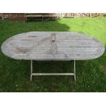 A Neptune Classic weathered teak garden table of oval form with open slatted top raised on folding x