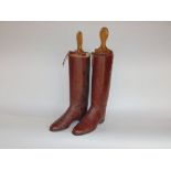 A pair of vintage brown leather riding boots with fitted wooden stretchers