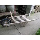 A vintage wooden barrow/hand cart with open slatted bed yoke shaped rail and later hard rubber tyre