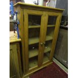 A stripped pine floorstanding side cabinet enclosed by a pair of rectangular moulded panelled