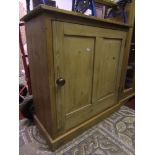 A low stripped pine side cupboard enclosed by a twin rectangular panelled doors, the interior fitted