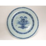 A 19th century tin glazed earthenware charger in the Delft manner with blue and white painted