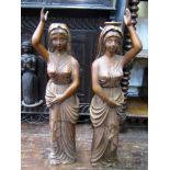 A pair of carved wooden pilasters in the form of classically draped female figures with trailing