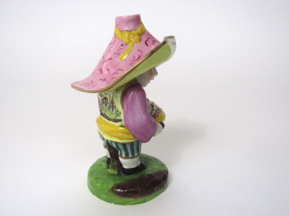 A 19th century figure of a Mansion House dwarf, in the Derby style, wearing a pink hat with yellow - Image 2 of 3