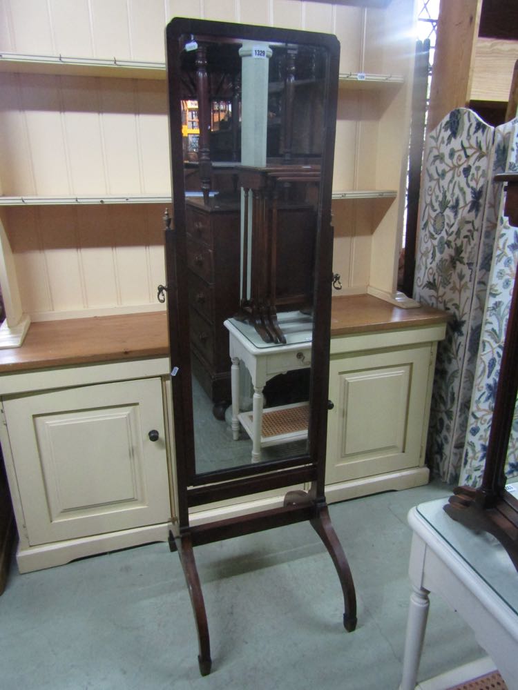 A traditional cheval glass with brass fittings on swept supports