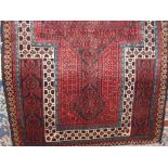 A Balochi rug decorated with a geometric red pattern upon a blue ground, 135 x 83cm