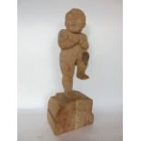 A carved wooden figure of a nude child on one leg, 36 cm high approx.