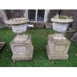 A pair of Victorian clay urns with geometric detail raised on later plinths