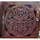 A Chinese carved hardwood panel of square cut form, the central medallion with floral and pierced