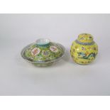 An oriental yellow ground shallow bowl and cover with polychrome painted floral detail and four